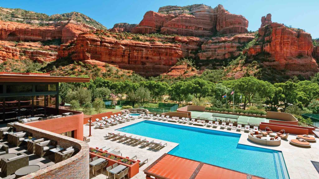 a pool with chairs and a large red rock mountain