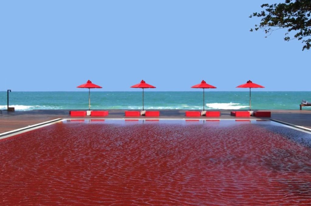a pool with red umbrellas and chairs
