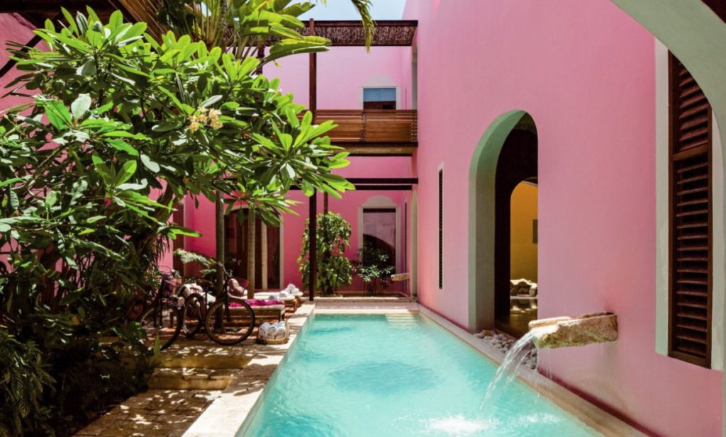 a pool with a pink wall and a pink building