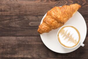 a croissant and a cup of coffee on a plate